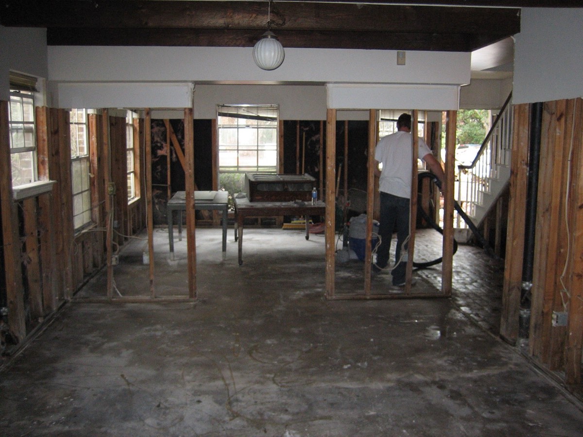 A worker cleaning the gutted interior of an Uptown New Orleans home following Hurricane Katrina flood damage — the first step in how to clean after a flood